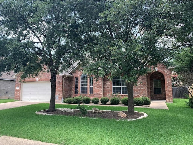 view of front of property with a garage, concrete driveway, a front lawn, and brick siding