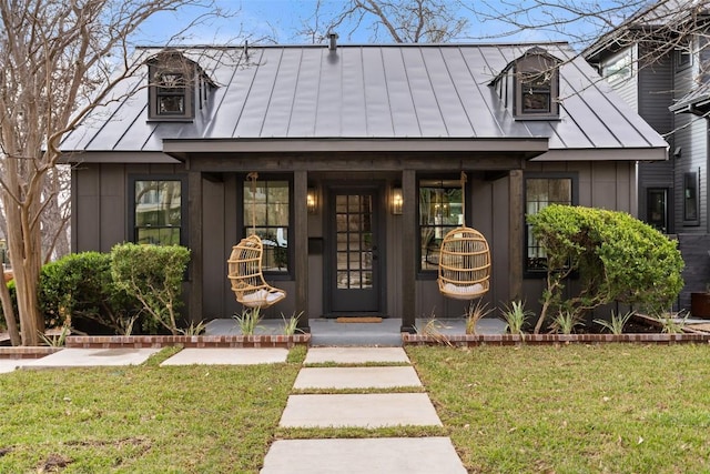 view of front of property featuring a standing seam roof, a front lawn, metal roof, and board and batten siding