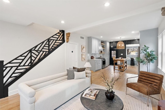 living room with light wood-style flooring, recessed lighting, visible vents, baseboards, and stairs