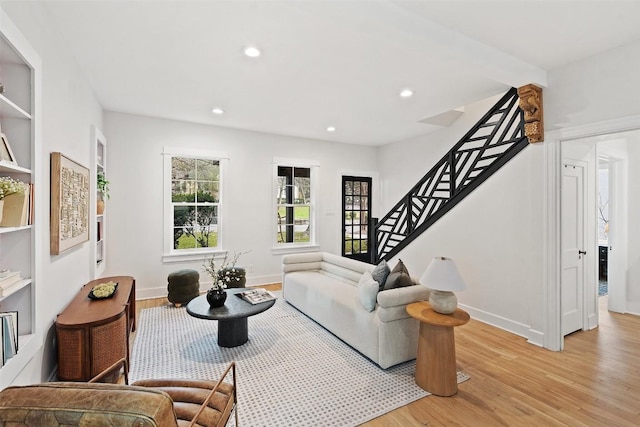 living area with recessed lighting, light wood-style flooring, baseboards, and stairs