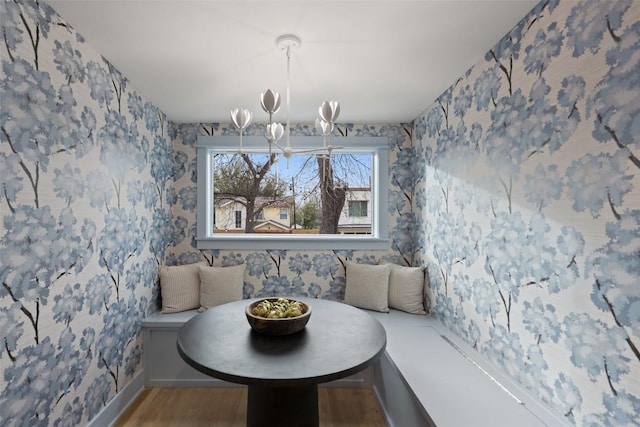 dining room featuring wallpapered walls, breakfast area, wood finished floors, and an inviting chandelier