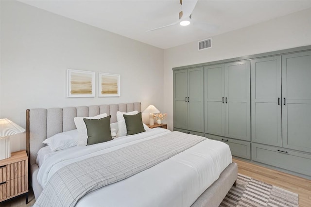 bedroom with light wood-type flooring, ceiling fan, visible vents, and a closet