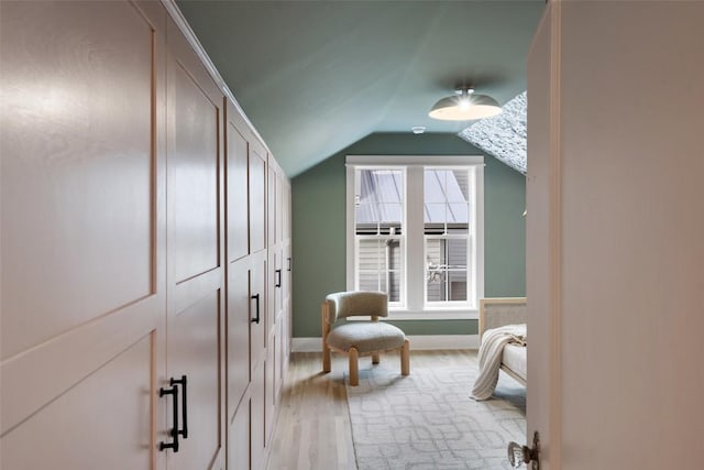 interior space with light wood-style floors, vaulted ceiling, and baseboards