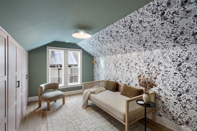 living area with vaulted ceiling, light wood finished floors, and baseboards