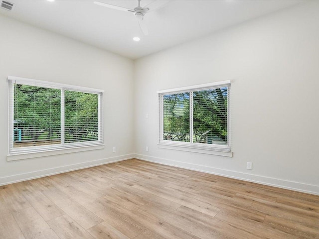 empty room featuring ceiling fan, light wood finished floors, visible vents, and baseboards