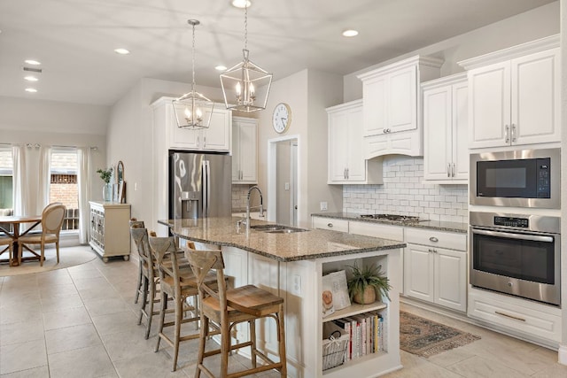 kitchen with stone counters, stainless steel appliances, a sink, white cabinets, and tasteful backsplash