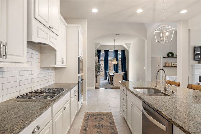 kitchen with white cabinets, appliances with stainless steel finishes, a sink, a notable chandelier, and backsplash