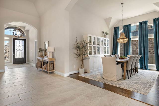 entryway featuring an inviting chandelier, baseboards, arched walkways, and high vaulted ceiling