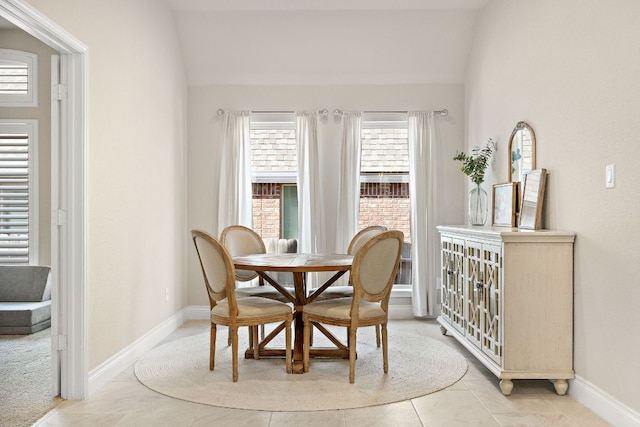 dining room featuring vaulted ceiling and baseboards