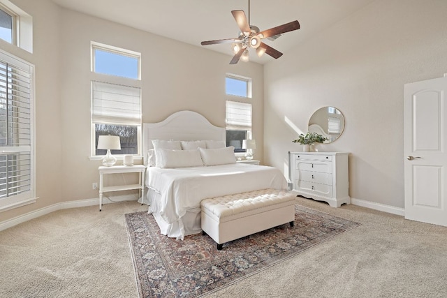 carpeted bedroom featuring a ceiling fan, multiple windows, and baseboards