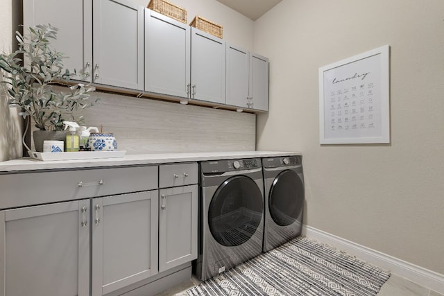 laundry room featuring baseboards, cabinet space, and washer and dryer