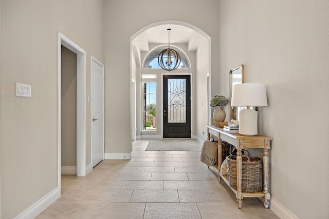 entrance foyer featuring arched walkways, a high ceiling, baseboards, and an inviting chandelier