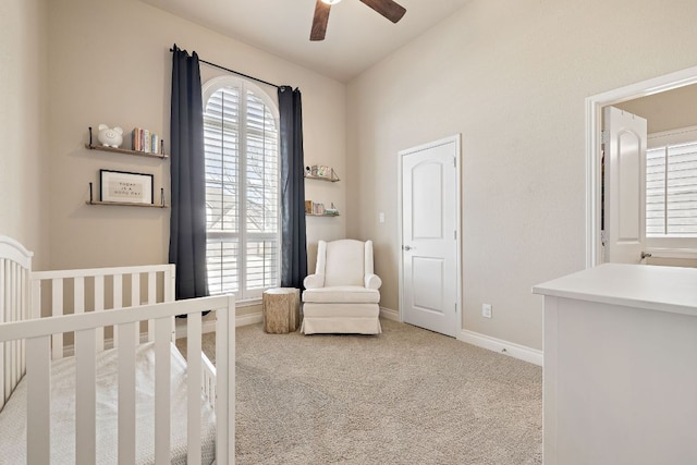 carpeted bedroom with a crib, ceiling fan, multiple windows, and baseboards