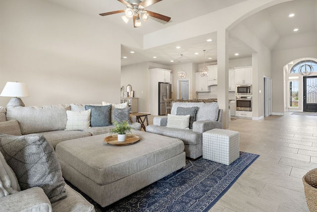 living room featuring arched walkways, ceiling fan, baseboards, and recessed lighting