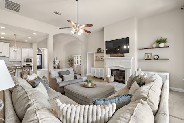 living room featuring a fireplace, visible vents, arched walkways, and recessed lighting