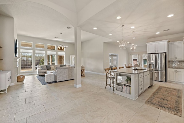 kitchen with open shelves, stainless steel appliances, open floor plan, a sink, and light stone countertops