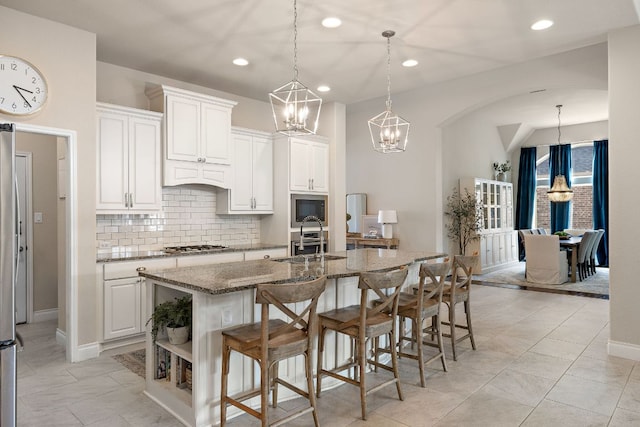 kitchen featuring stainless steel appliances, a sink, a kitchen breakfast bar, decorative backsplash, and dark stone counters