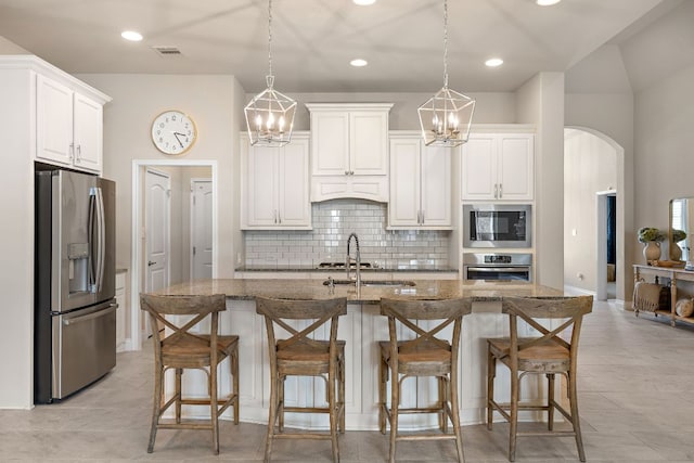 kitchen with appliances with stainless steel finishes, arched walkways, visible vents, and dark stone countertops