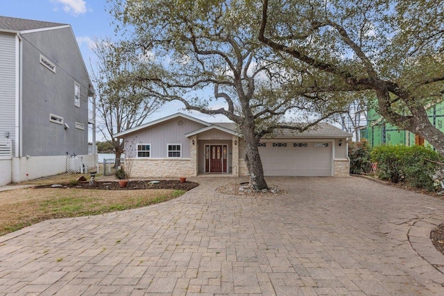 view of front of home with stone siding, decorative driveway, and an attached garage