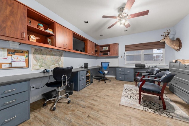 office featuring built in desk, light wood-type flooring, and a ceiling fan