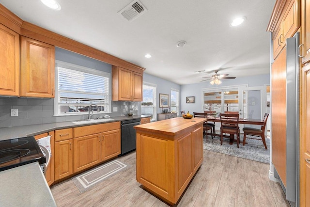 kitchen with a sink, visible vents, black dishwasher, wooden counters, and light wood-type flooring