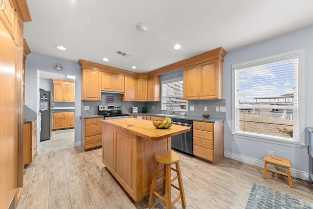 kitchen featuring wood counters, visible vents, light wood-style floors, appliances with stainless steel finishes, and a center island