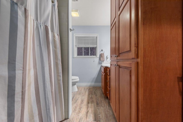 full bathroom featuring a shower with shower curtain, toilet, vanity, wood finished floors, and baseboards