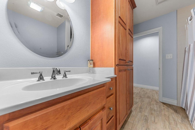 bathroom featuring baseboards, visible vents, wood finished floors, and vanity