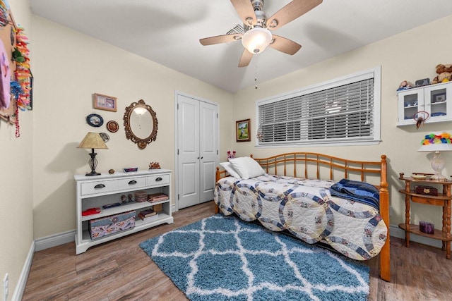 bedroom featuring a closet, wood finished floors, a ceiling fan, and baseboards