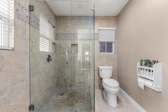 bathroom with a stall shower, baseboards, toilet, and tile patterned floors