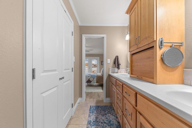 ensuite bathroom featuring double vanity, ensuite bathroom, ornamental molding, a sink, and tile patterned flooring