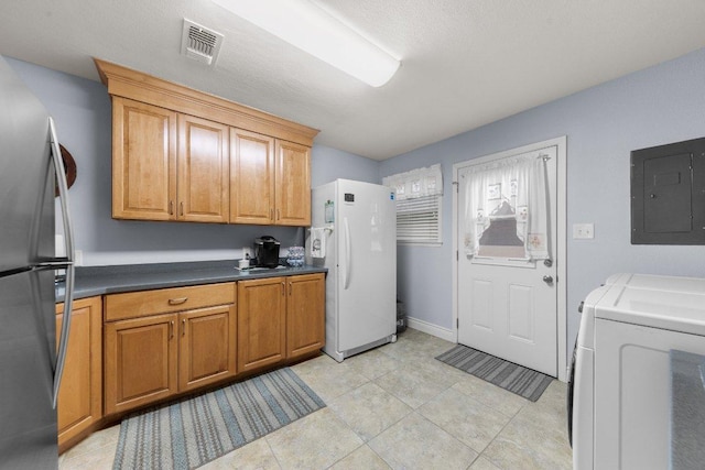 kitchen with freestanding refrigerator, electric panel, visible vents, and dark countertops