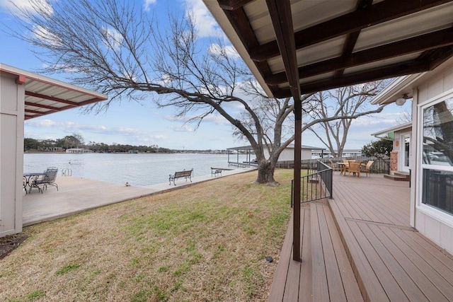 wooden deck featuring a water view, a lawn, and a patio