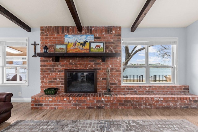 living area with beamed ceiling, a fireplace, wood finished floors, and baseboards