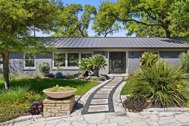 view of front of house featuring a standing seam roof, metal roof, and brick siding