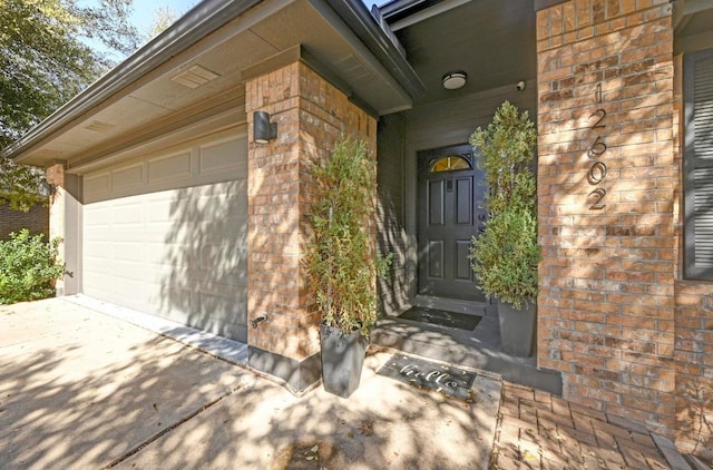 property entrance with brick siding and an attached garage