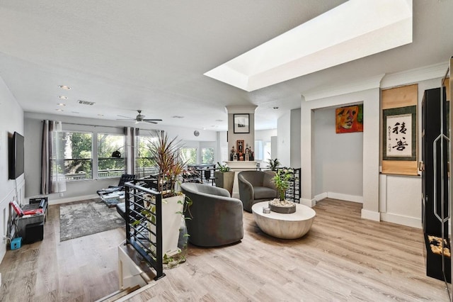 living area featuring visible vents, a ceiling fan, light wood-style flooring, and baseboards