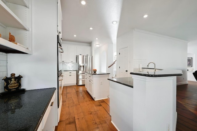 kitchen with a kitchen island, light wood-style floors, stainless steel refrigerator with ice dispenser, tasteful backsplash, and dark countertops