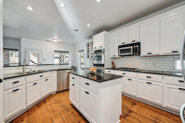 kitchen featuring a center island, stainless steel appliances, visible vents, light wood-style floors, and a sink