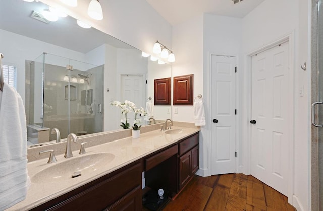 full bathroom featuring wood finished floors, a stall shower, a sink, and visible vents