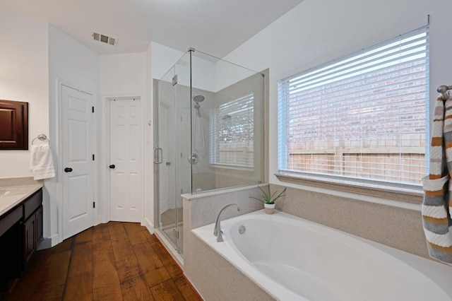 full bath featuring a stall shower, visible vents, wood finished floors, a garden tub, and vanity