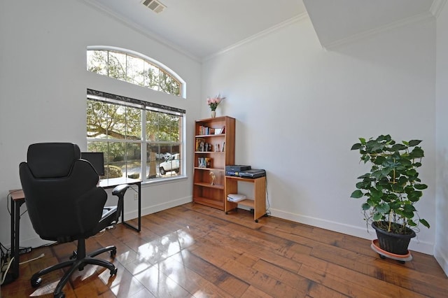 office area with wood-type flooring, visible vents, crown molding, and baseboards