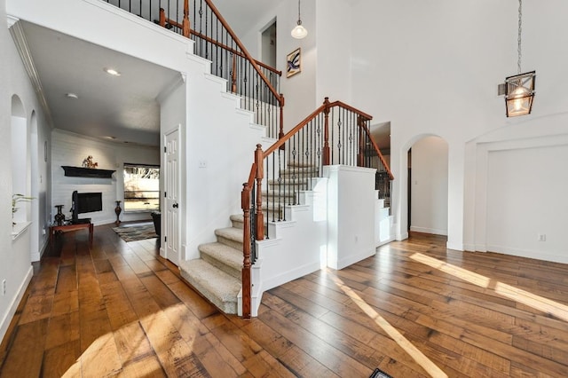 stairway with hardwood / wood-style flooring, baseboards, a fireplace, and arched walkways