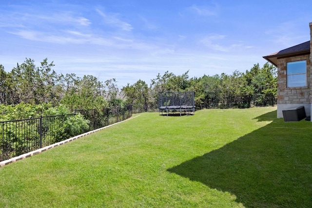 view of yard featuring a trampoline and a fenced backyard