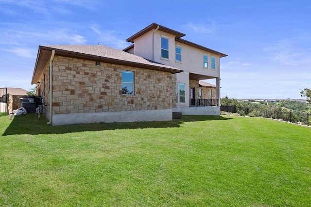 back of property with stone siding, fence, and a yard