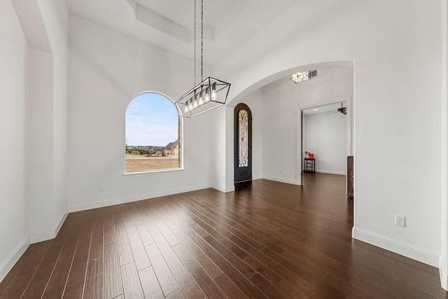 interior space featuring arched walkways, ceiling fan, dark wood-style flooring, and baseboards