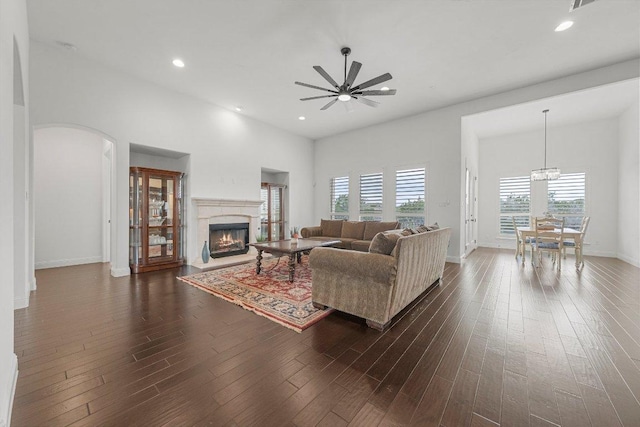 living area with arched walkways, dark wood-type flooring, a glass covered fireplace, and recessed lighting