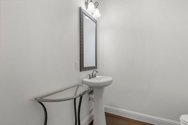 bathroom with wood finished floors, toilet, and baseboards