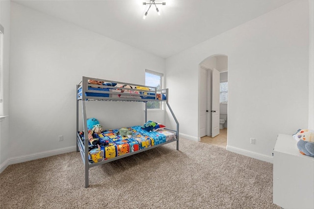 carpeted bedroom with baseboards and arched walkways