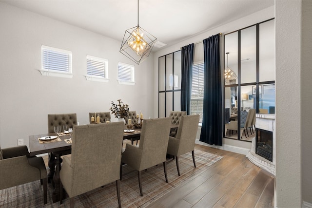 dining room with a chandelier, a glass covered fireplace, wood finished floors, and a healthy amount of sunlight